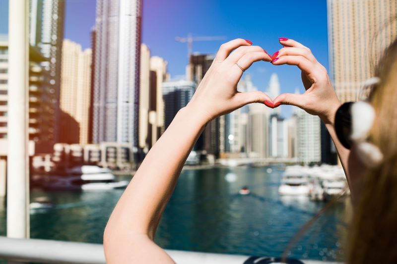 Shows Heart with Her Fingers before Skyscrapers Dubai